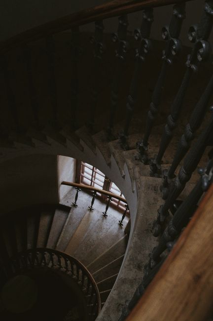 A captivating high-angle view of a spiral staircase with dark metal handrails in a dimly lit interior setting.
