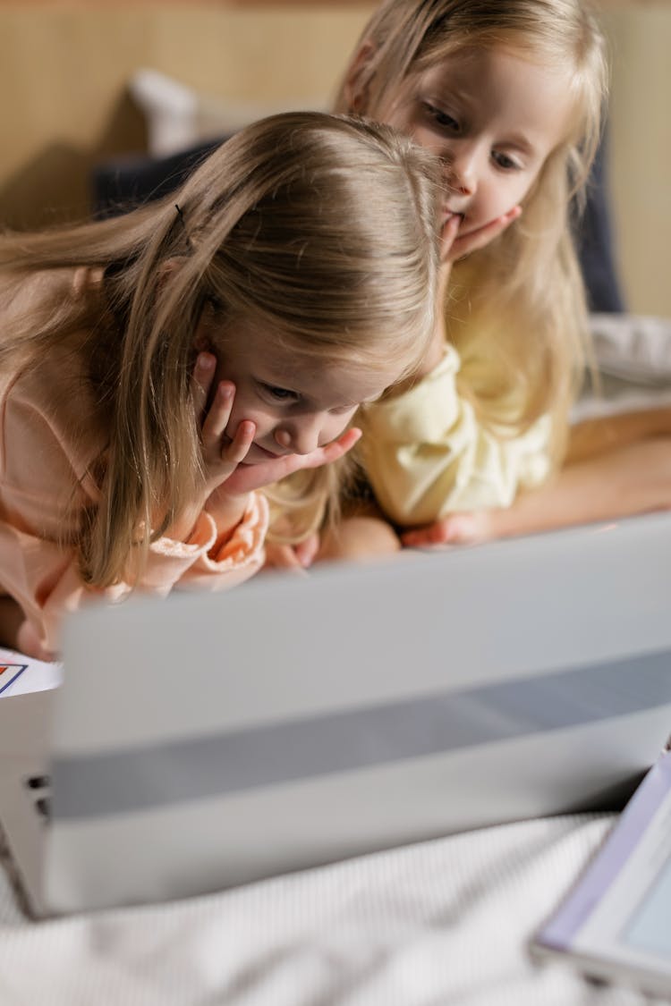 Twin Girls Looking At A Laptop Screen With Enthusiasm