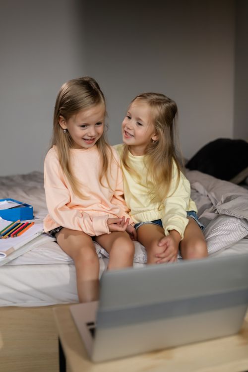 Free Two young sisters sitting together at home on a laptop, focused on online learning. Stock Photo