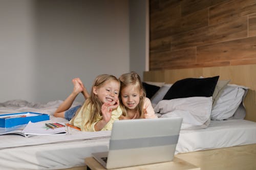 Two Girls Having an Online Class while Lying on the Bed