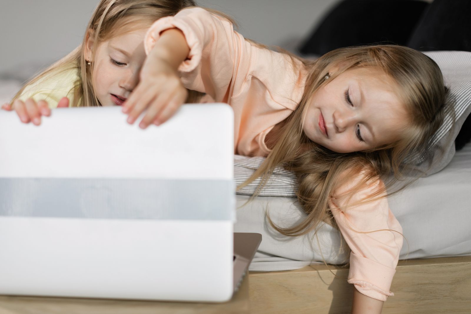 Two young girls sitting together and using a laptop for an online learning session at home
