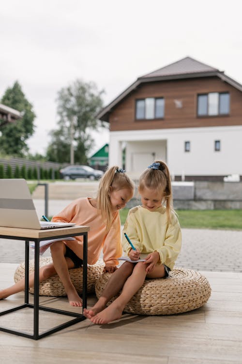 Two Girls Having an Online Class while Writing