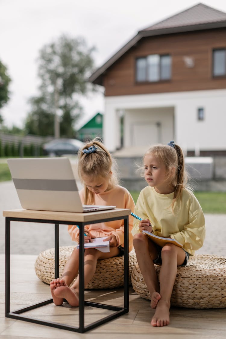 Two Girls Having An Online Class While Writing