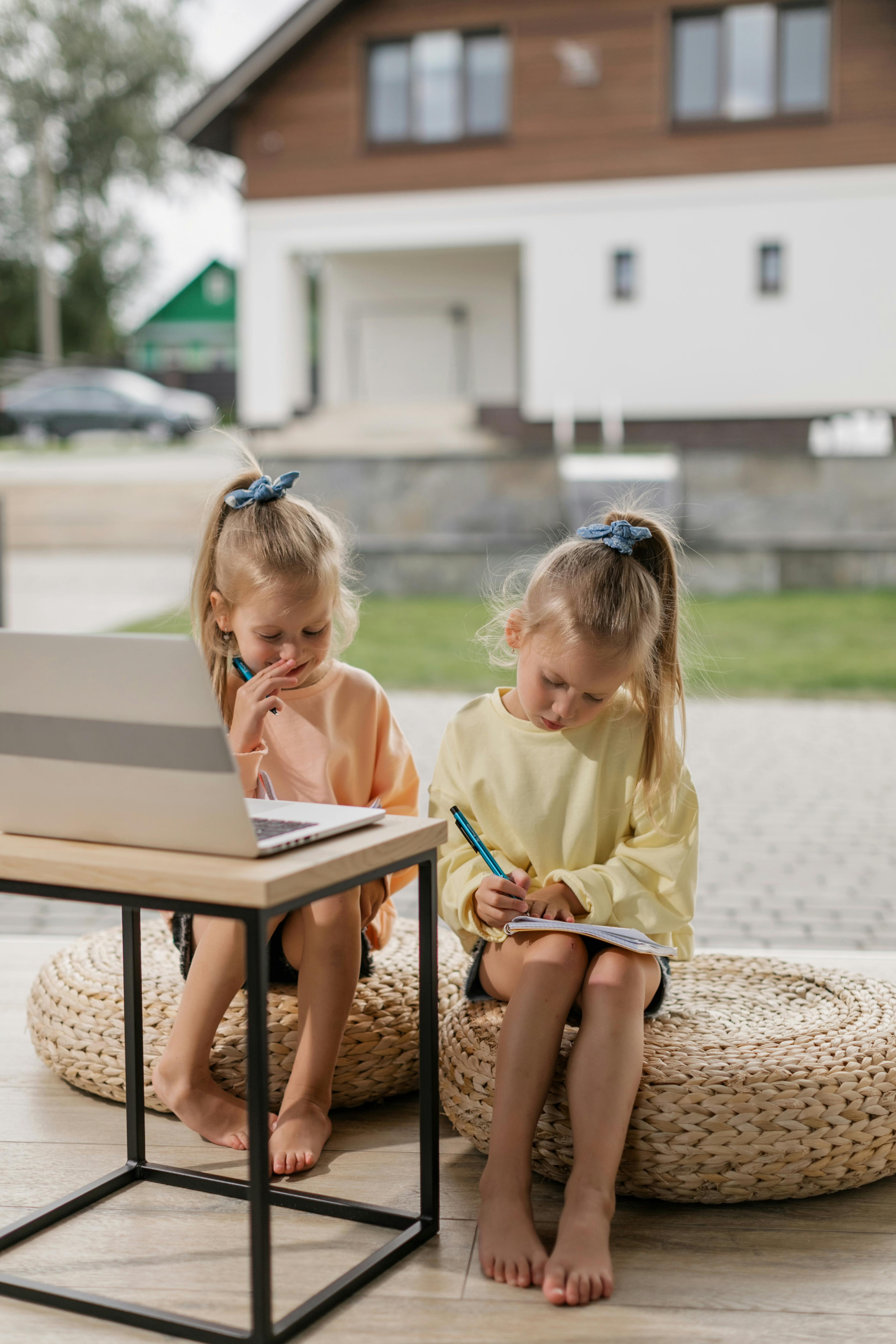 two girls having an online class while writing