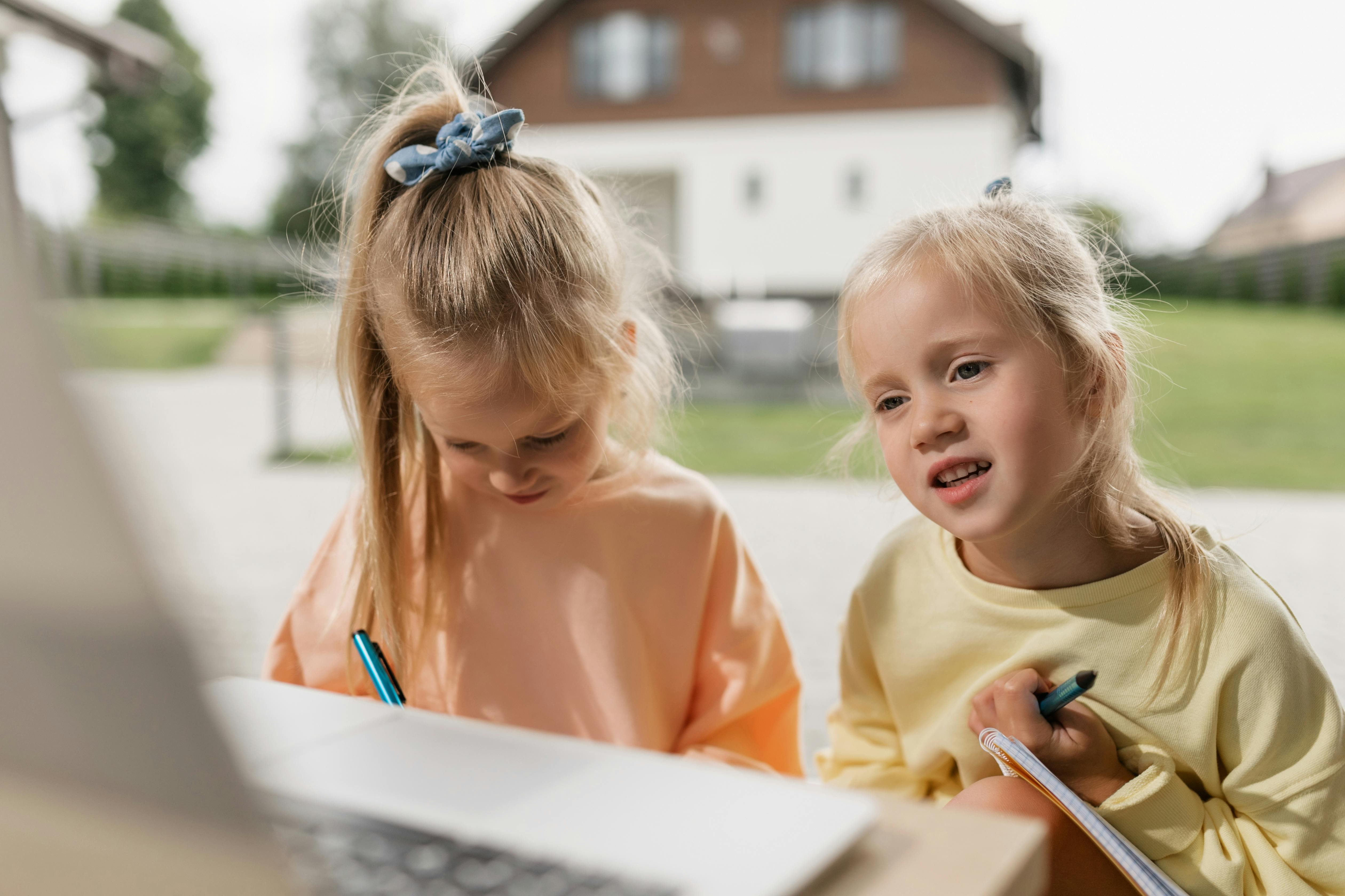 close up shot of two girls having an online class while writing