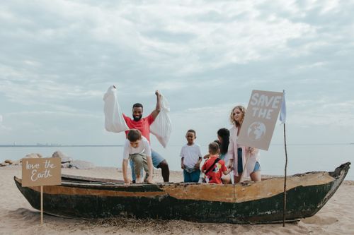 Free Group of people cleaning beach to promote Earth conservation with signs. Stock Photo
