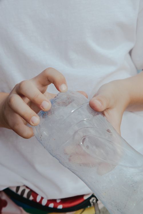 Free A close-up of hands holding an empty plastic bottle, focusing on recycling concepts. Stock Photo
