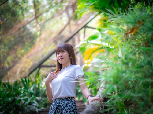 Woman in White Shirt and Floral Skirt Standing Near Green Plants