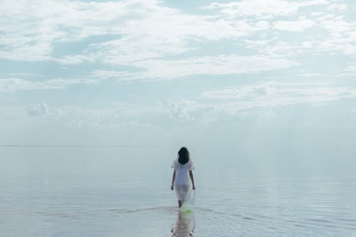 Free Woman in Plastic Dress Walking into the Water Stock Photo