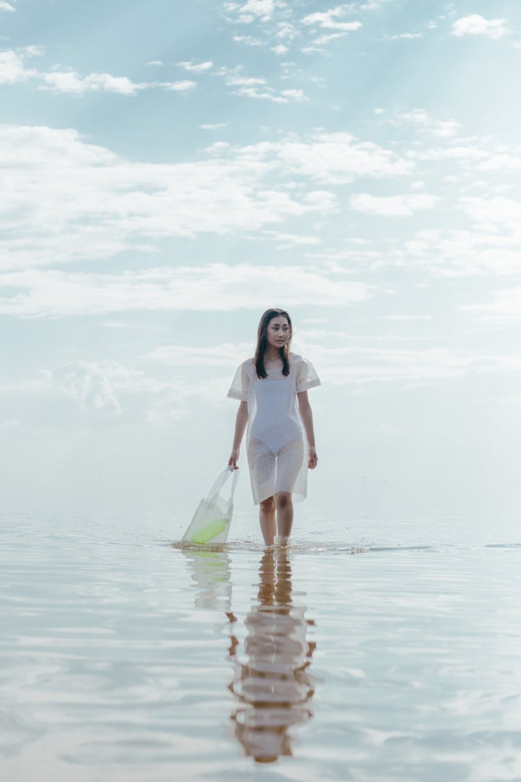 A Woman In Plastic Dress Holding A Plastic Bag In The Water