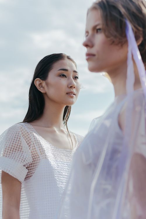 Free Two women posing elegantly in modern, translucent outfits, showcasing contemporary fashion trends. Stock Photo