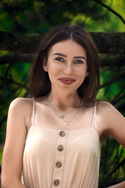 Free Beautiful young woman smiling warmly in an outdoor portrait with a natural lush background. Stock Photo