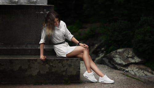 A Woman Posing While Sitting on a Concrete Bench