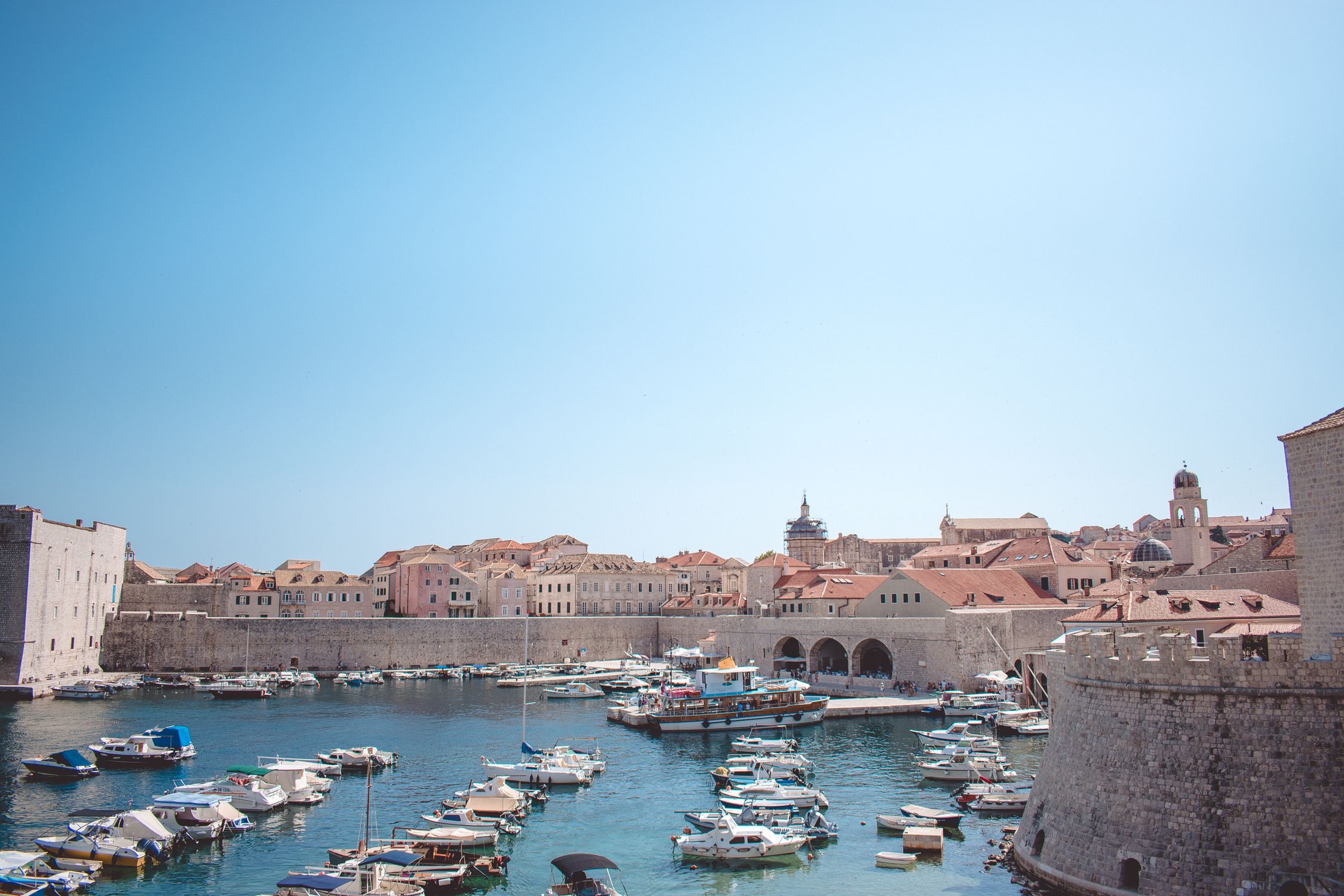 Charming view of the historic harbor in Dubrovnik, Croatia, with boats and medieval architecture.