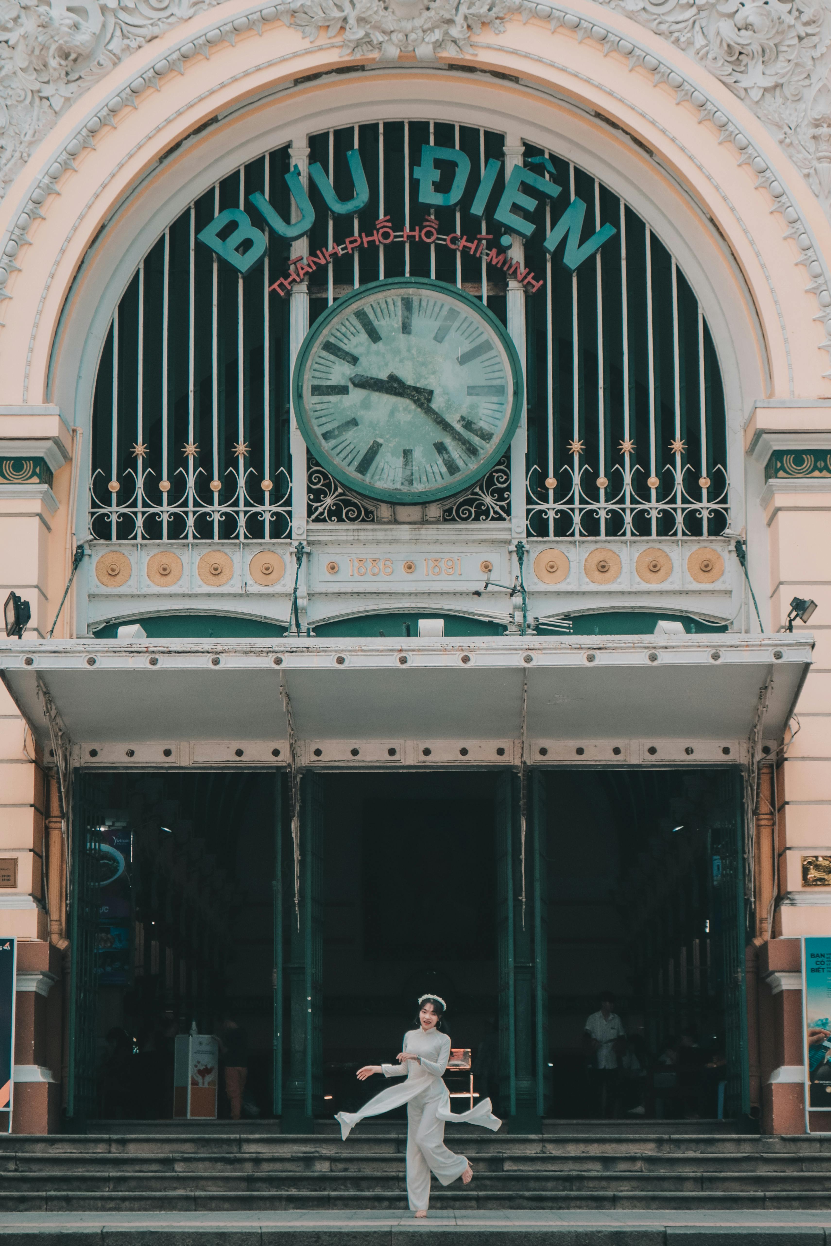 a woman standing on front of saigon central post office building