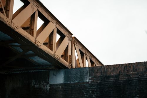 Free A low angle view of a metal bridge with a brick wall, showcasing industrial architecture. Stock Photo