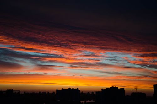 Free Captivating twilight sky over a cityscape with vibrant orange and blue hues. Stock Photo