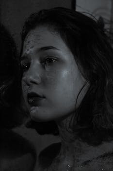 Close-up monochrome portrait of a young woman with dramatic shadows and texture.