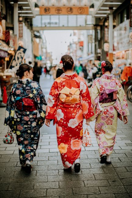 Three women in vibrant kimonos walking down a bustling street in Taito City, Tokyo, Japan.