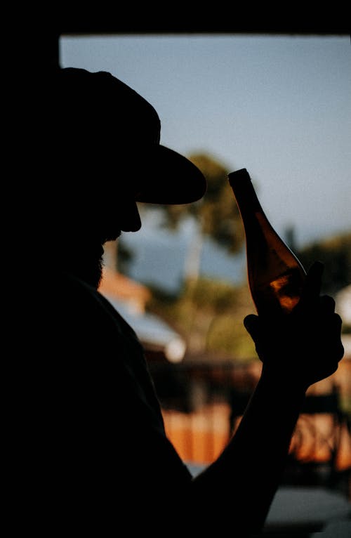 Silhouette of a Person Holding a Bottle of Beer
