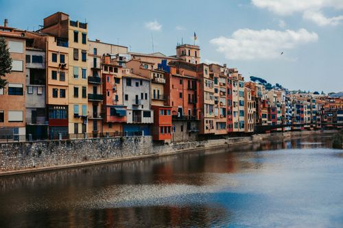 Free Vibrant apartment facades line the Onyar River in Girona, Spain, reflecting architectural beauty. Stock Photo