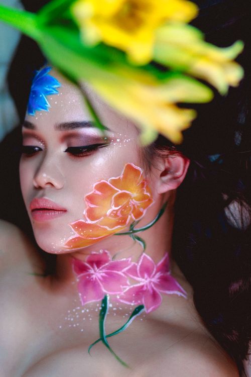 Free A creative portrait of a woman with vivid floral face paint and artistic makeup. Stock Photo