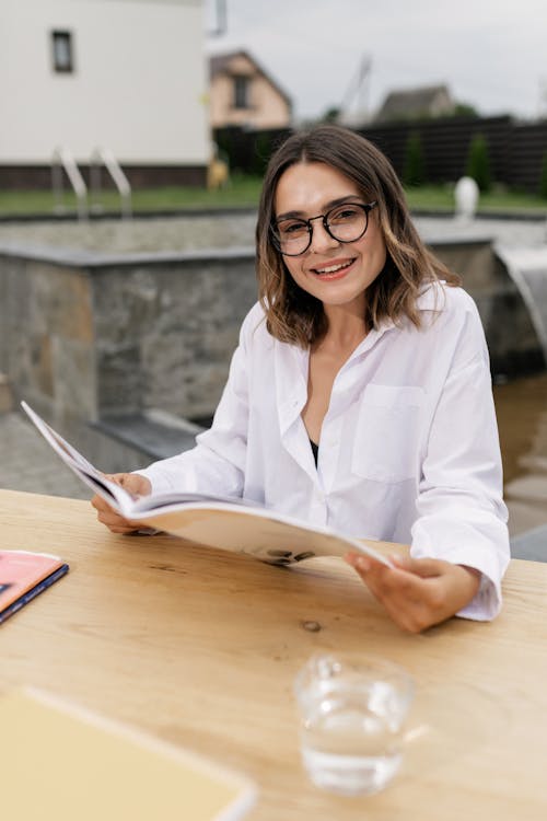 Woman in White Long Sleeve Shirt Sitting by the Table