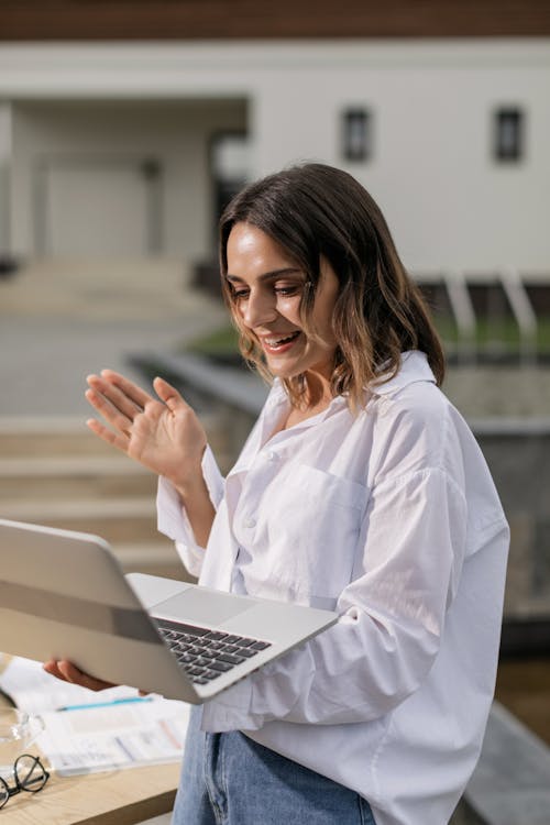 A Woman in White Long Sleeves Holding a Laptop