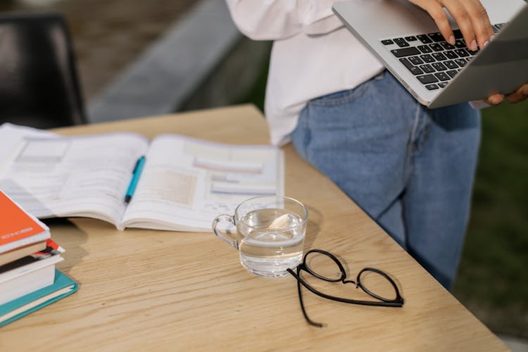 Eyeglasses And Cup Of Water On Wooden Table