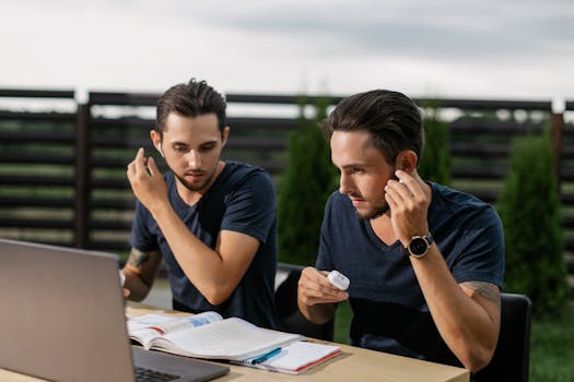 Twin brothers participating in an outdoor virtual class using laptops and headphones.