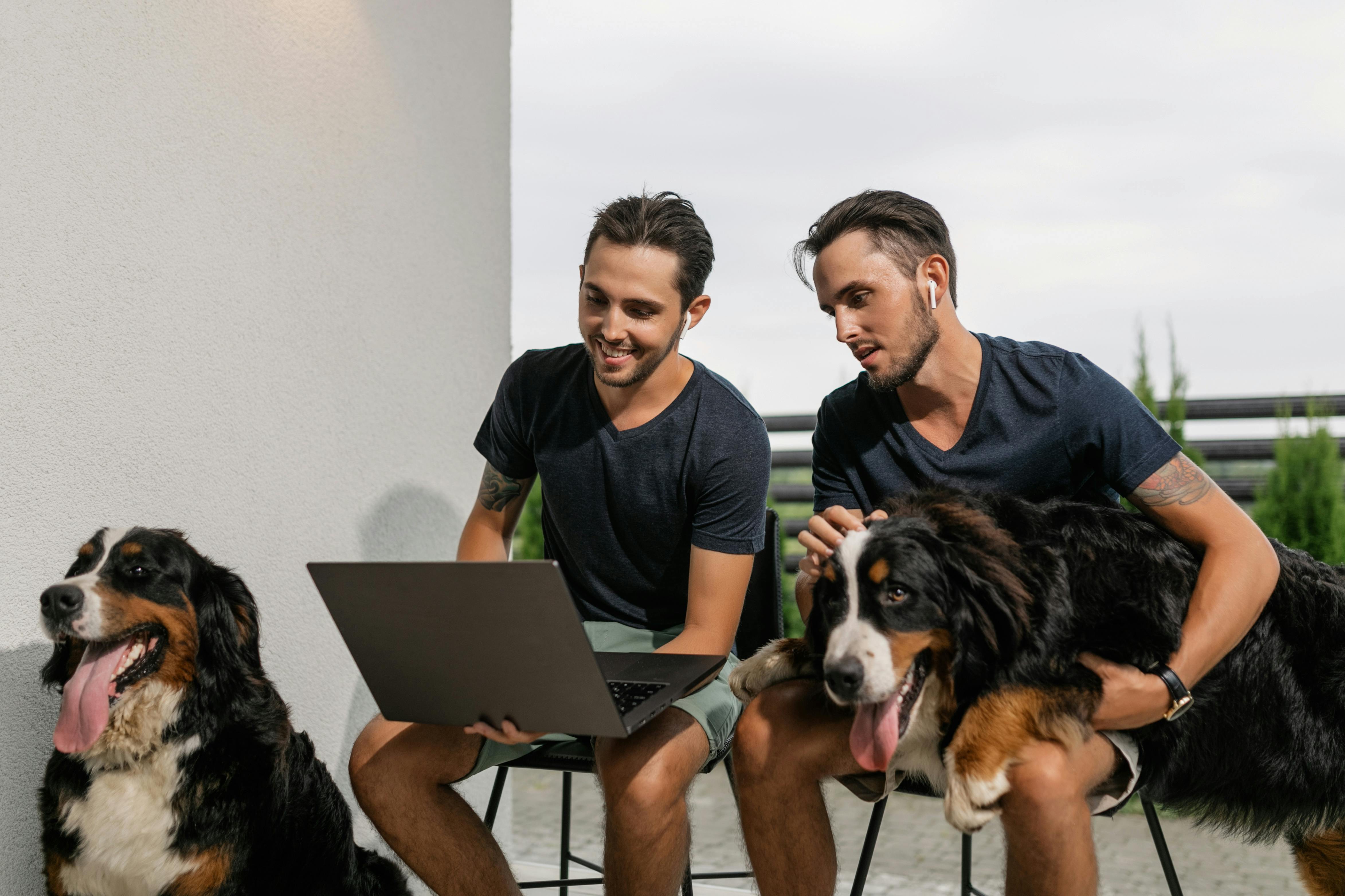 twins looking at a laptop together while with their pets