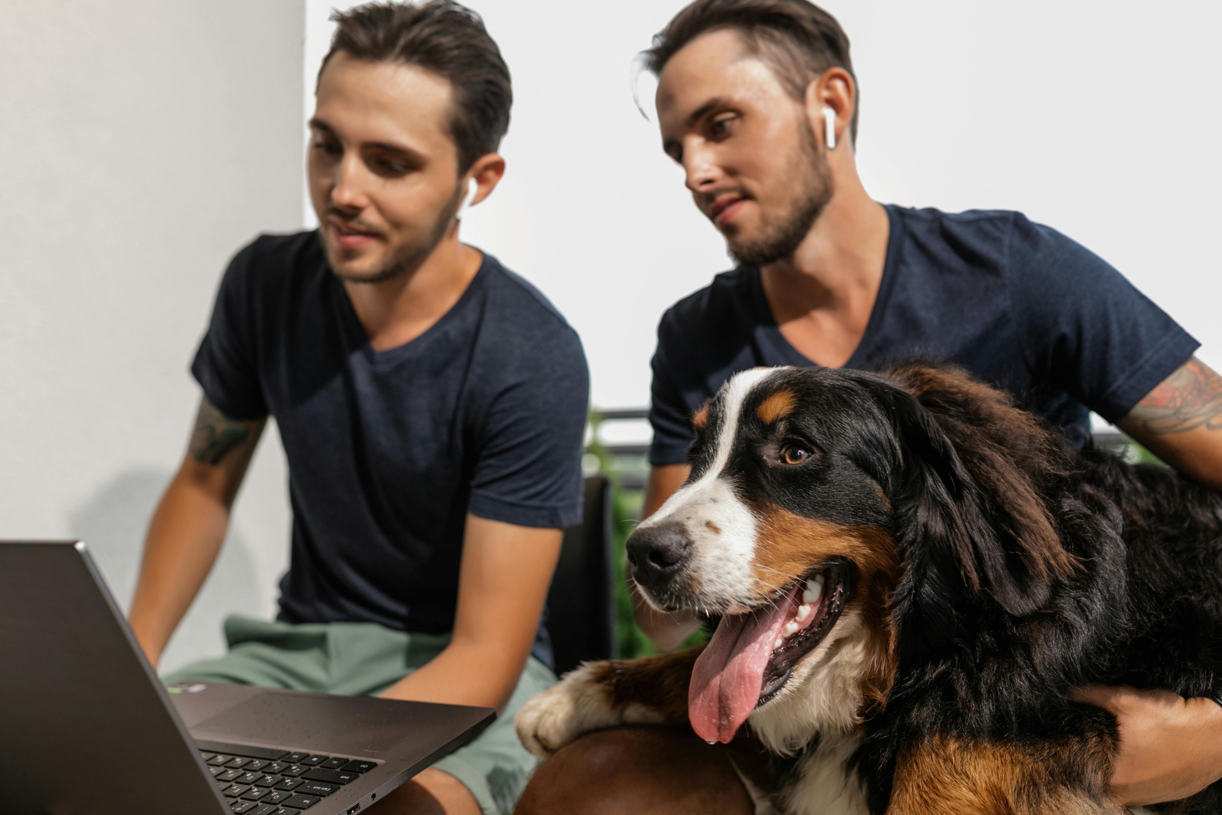 twins looking at laptop while holding a dog