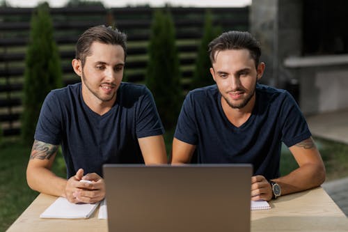 Twin Brothers in Blue V-Neck Shirts Looking at Laptop Screen