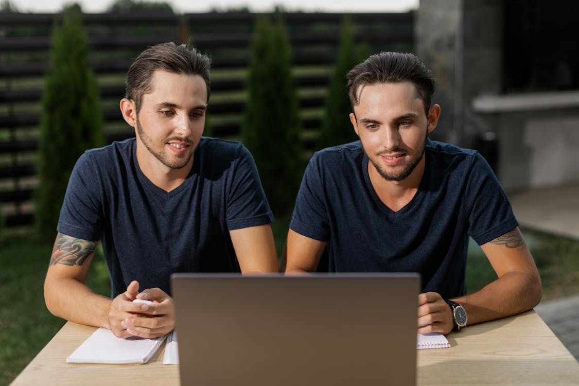 Free Twin Brothers in Blue V-Neck Shirts Looking at Laptop Screen Stock Photo