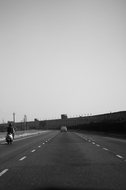 Monochrome Photo of a Vehicle and Motorcycle on Highway