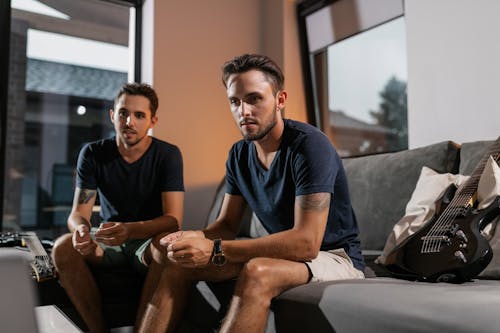 Two Men Sitting on Gray Couch and Watching 