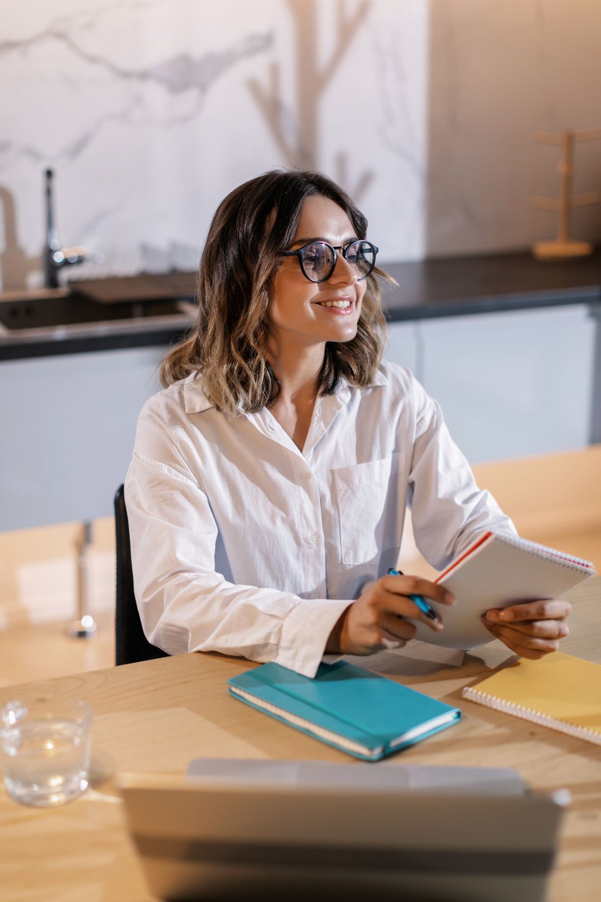 Assistant taking notes at a desk with a laptop