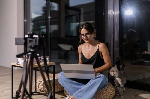 Free Woman working from home with laptop and cat beside her indoors. Ideal for online education and remote work concepts. Stock Photo