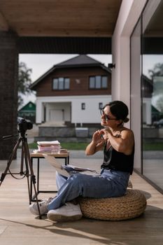 Woman reviewing photos on a laptop at home with a camera setup in natural light.