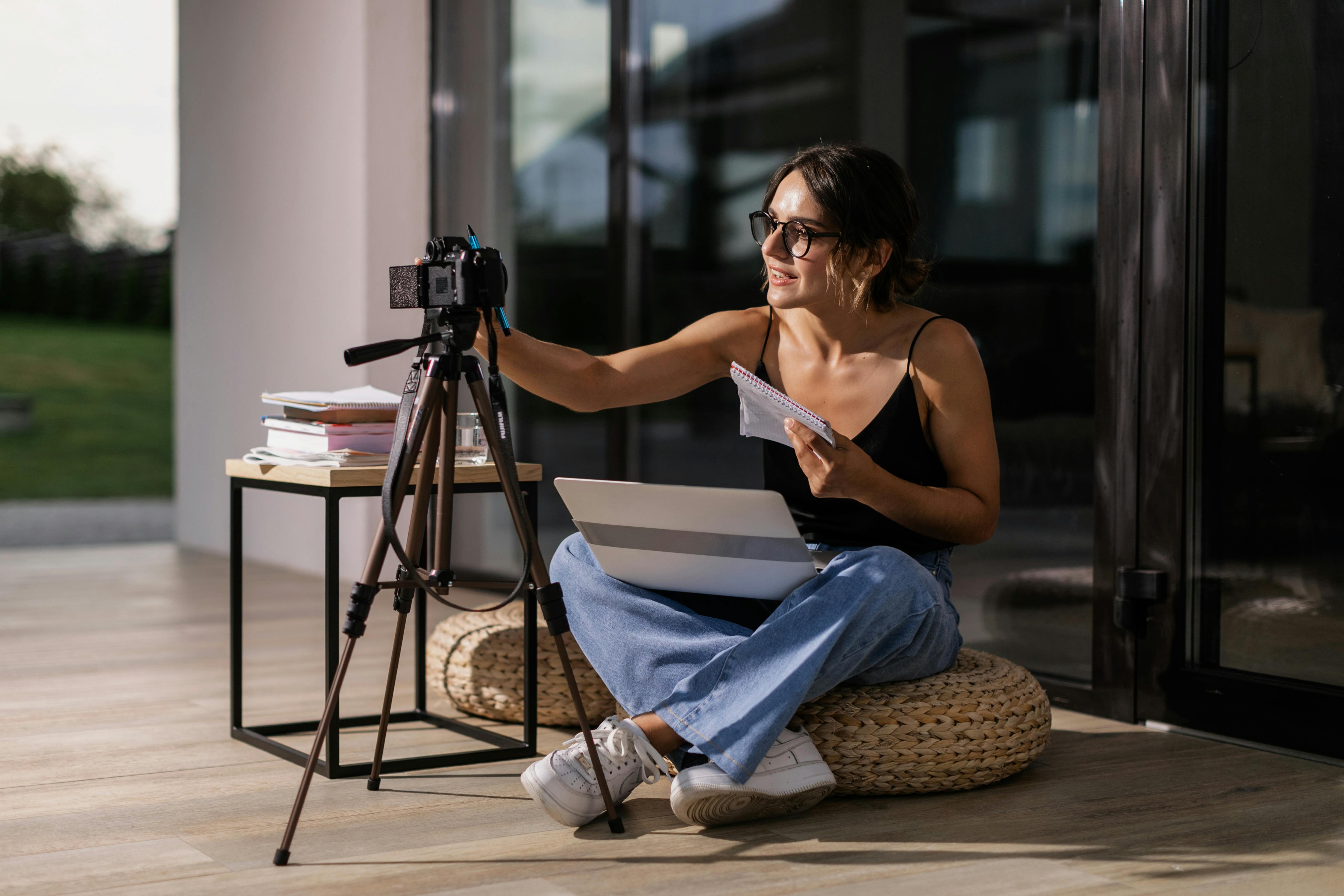 Adult woman setting up a camera indoors for an online education session with a laptop.