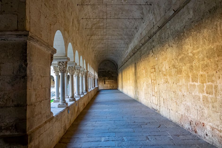 A serene stone corridor of a historic monastery in Sant Cugat, bathed in natural light.