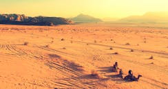 在引人注目的温暖色调沙漠场景中，骆驼和骑手与雄伟的山脉形成鲜明对比