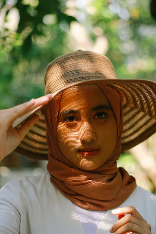 Woman in Brown Hijab Holding her Brown Woven Hat