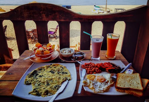在海滩边俯瞰海景，享用海滨早餐，包括鸡蛋、新鲜果汁和水果沙拉