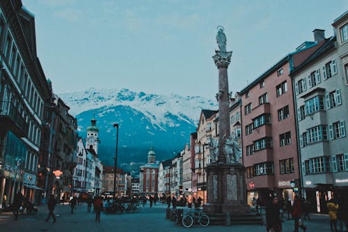 Brown and White Concrete Buildings Near Snow Coated Mountain