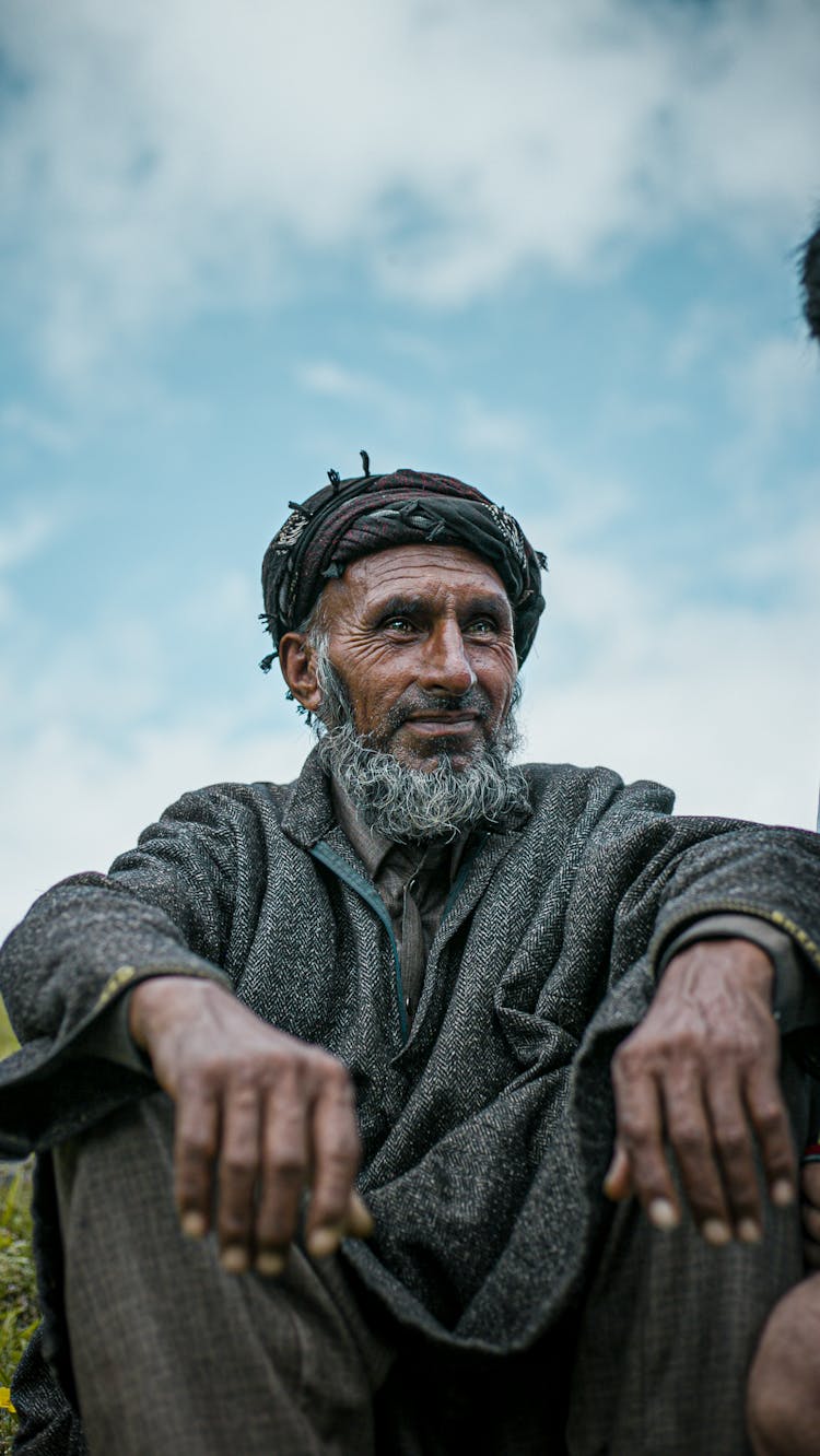 An Elderly Man In A Black Robe Sitting