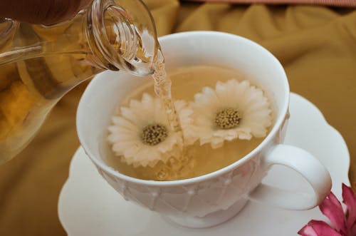 Clear Glass Pitcher Pouring Liquid on White Ceramic Cup