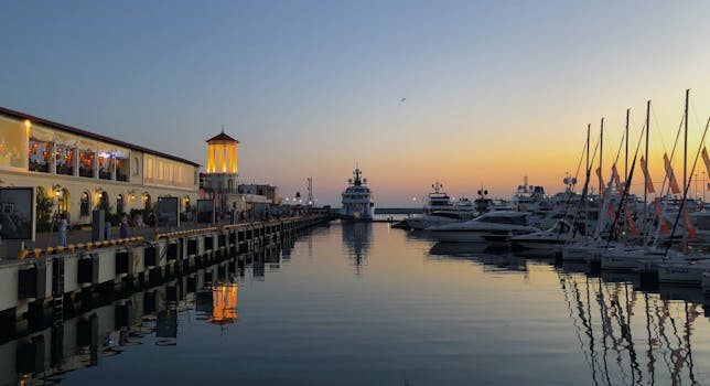 Beautiful sunset over the Sochi maritime station with boats docked at the pier, capturing a serene harbor view.