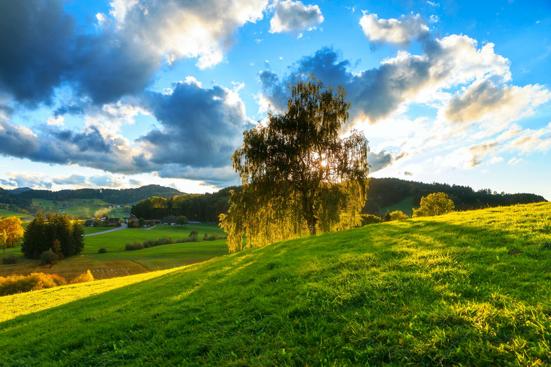 Scenic countryside view at sunset in Kirchberg, SG, Switzerland with vibrant fields and a dramatic sky.