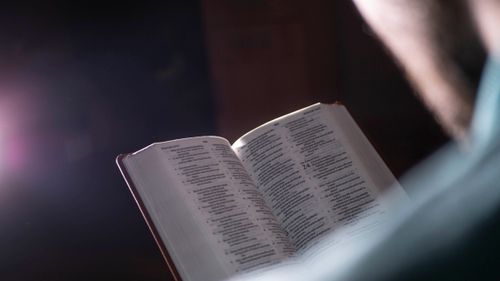 Free An open book with scripture pages visible in soft lighting, creating a serene atmosphere. Stock Photo